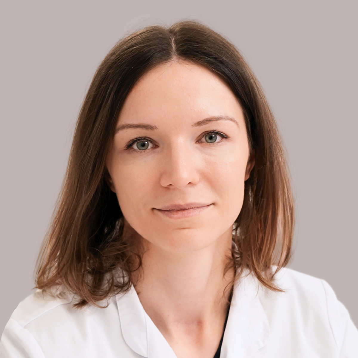 Portret lek. Aleksandry Góreckiej, specjalistki dermatologii, wenerologii i medycyny estetycznej w warszawskim centrum FEBUMED, uśmiechnięta lekarka w profesjonalnym stroju medycznym na jasnym tle.