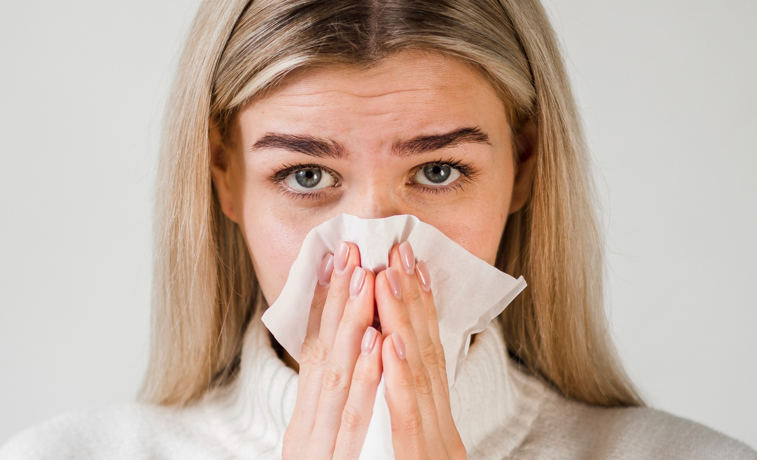 Kobieta wycierająca nos chusteczką.