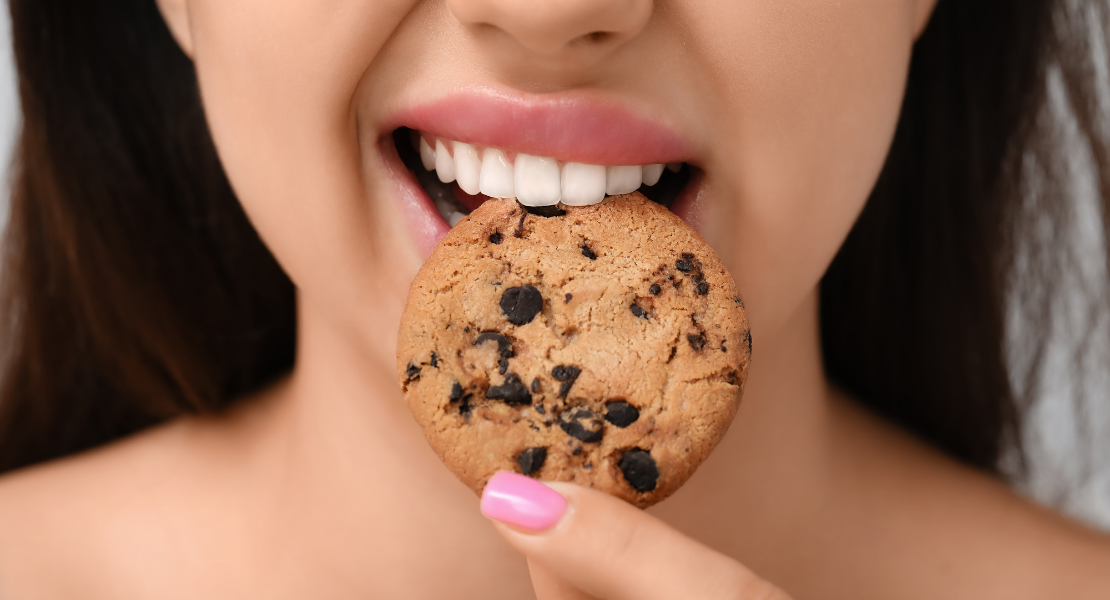 Kobieta nadgryza kruche, okrągłe ciasteczko.